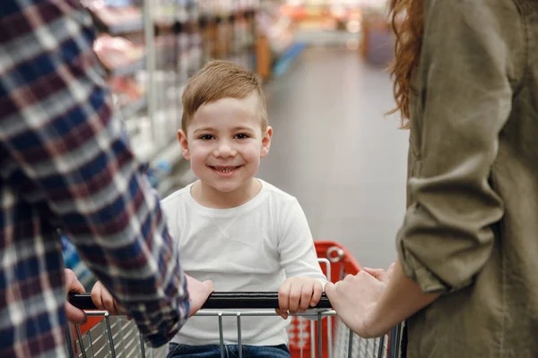 Giovane ragazzo seduto sul carrello della spesa — Foto Stock