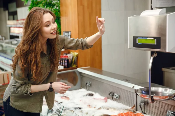 Zijaanzicht van gelukkige vrouw kiezen vis — Stockfoto