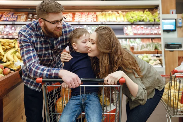 Pareja joven con hijo en el supermercado — Foto de Stock