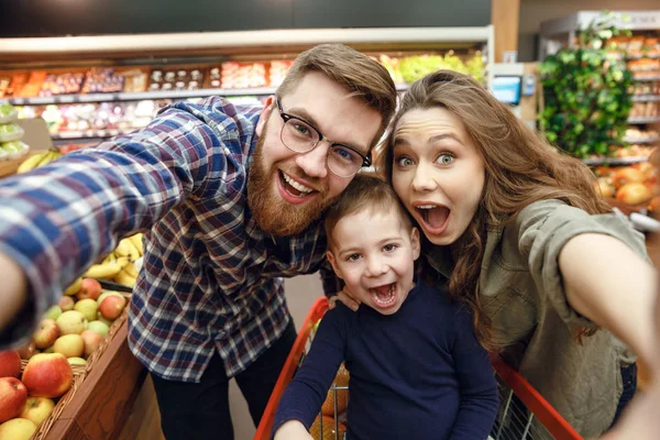 Jovem família feliz fazendo foto no supermercado — Fotografia de Stock