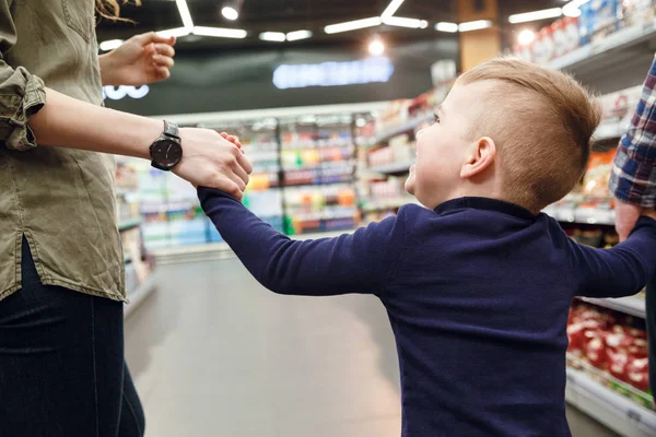 Vista trasera de Young Son caminando con la madre en el supermercado —  Fotos de Stock