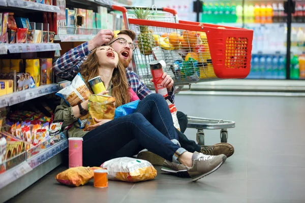 Linda pareja tratando de comer fichas en el suelo —  Fotos de Stock