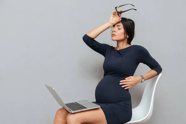 Aburrido mujer embarazada de negocios sentado sobre fondo gris —  Fotos de Stock