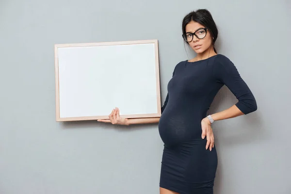 Señora de negocios embarazada concentrada sosteniendo espacio de copia en blanco . —  Fotos de Stock