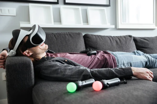 Happy man lies on sofa at home wearing 3d glasses. — Stock Photo, Image