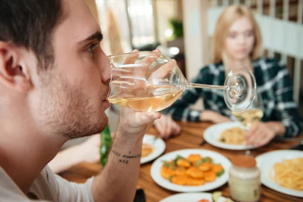 Мужчина обедает и пьет вино с друзьями на кухне — стоковое фото