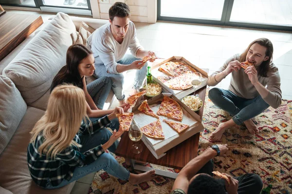 Вид зверху на п'ять друзів, які їдять піцу в будинку — стокове фото