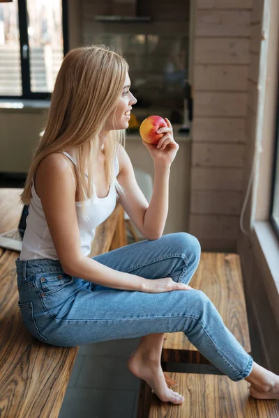 Linda jovem sentada em casa dentro de casa comendo maçã — Fotografia de Stock