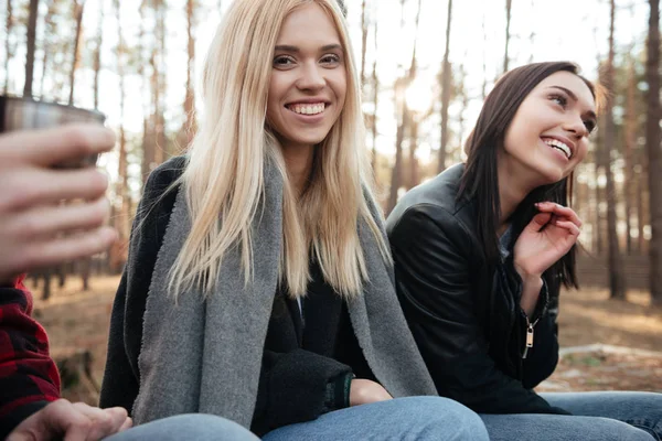 Fröhliche Gruppe von Freunden sitzt draußen im Wald. — Stockfoto