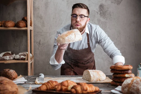 Homem concentrado padeiro em pé na padaria segurando pão — Fotografia de Stock
