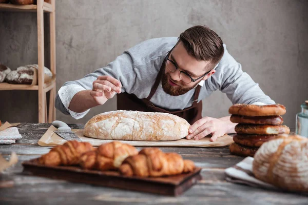 Concentrated man baker standing at bakery near bread. — Stock Photo, Image