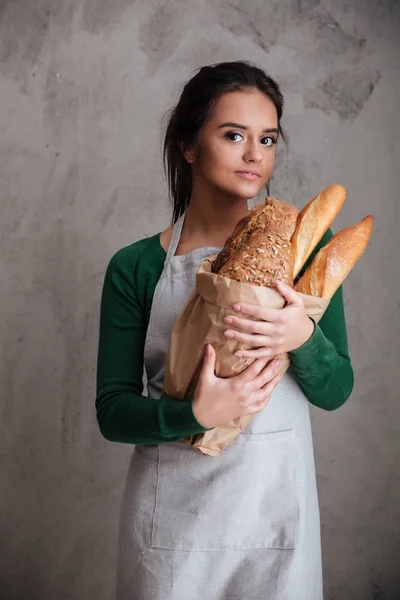 Jeune femme gaie boulanger debout et tenant du pain . — Photo