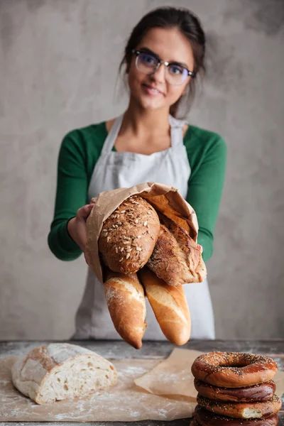 Imagen vertical del panadero hembra mostrando bolsa con pan —  Fotos de Stock