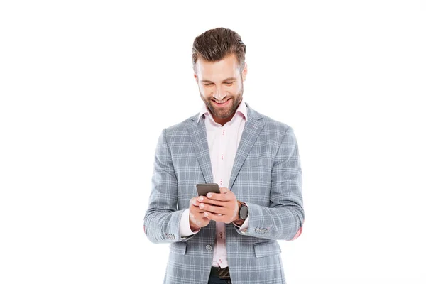 Feliz joven de pie aislado usando el teléfono móvil . — Foto de Stock