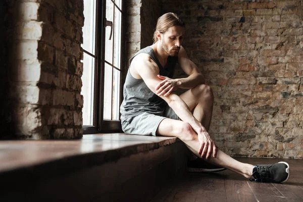 Retrato de un hombre de fitness que sufre de un dolor en las piernas —  Fotos de Stock