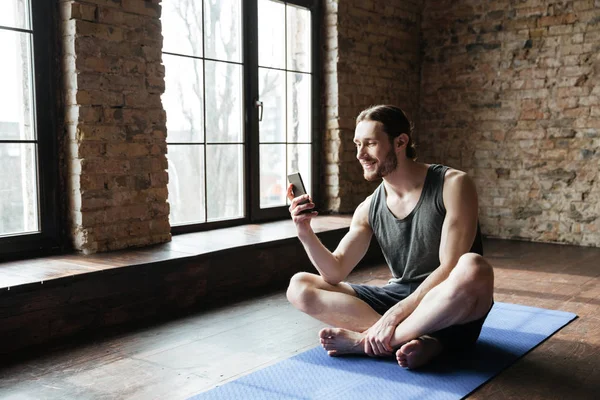 Сосредоточенный на улыбке спортсмен с мобильного телефона — стоковое фото