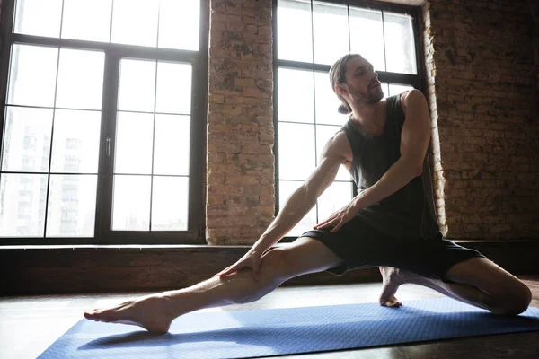 Retrato de um homem saudável esticando a perna antes do treino de ginástica — Fotografia de Stock