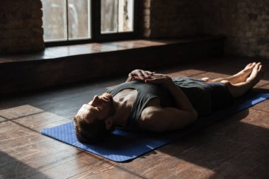 Yakışıklı genç güçlü sporcu spor salonunda yerde yatıyor