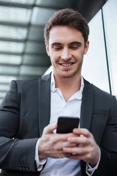 Sonriente joven hombre de negocios caminando cerca de centro de negocios charlando — Foto de Stock