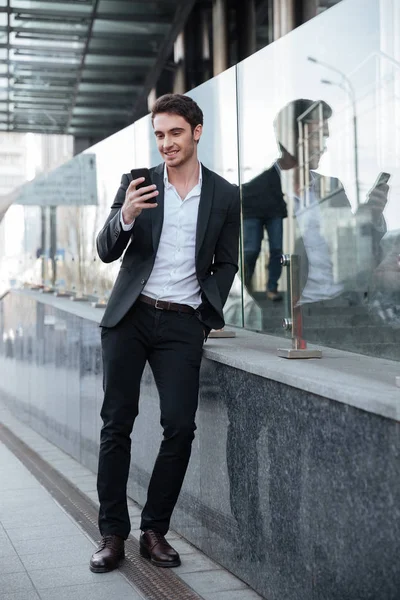 Sonriente joven empresario caminando cerca del centro de negocios . — Foto de Stock