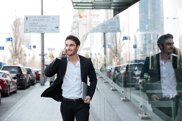 Sonriente joven empresario caminando cerca del centro de negocios — Foto de Stock