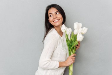 Çiçekli gri duvar üzerinde duran neşeli kadın