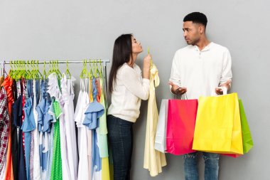 Bayan giyim alışveriş torbaları tutan karışık adamdan yalvarıyor.