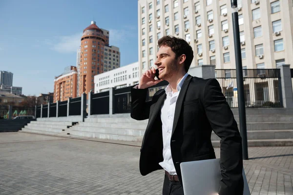 Feliz joven hombre de negocios caminando al aire libre hablando por teléfono . — Foto de Stock