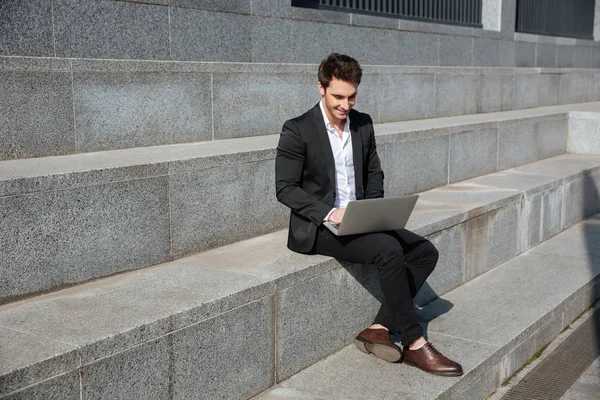 Smiling young businessman sitting outdoors. — Stock Photo, Image