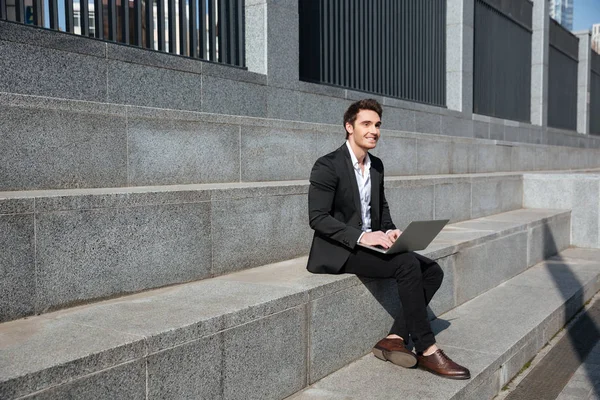Sonriente joven empresario sentado al aire libre . — Foto de Stock