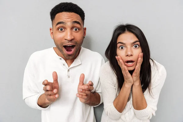 Schockiertes Liebespaar posiert über graue Wand — Stockfoto