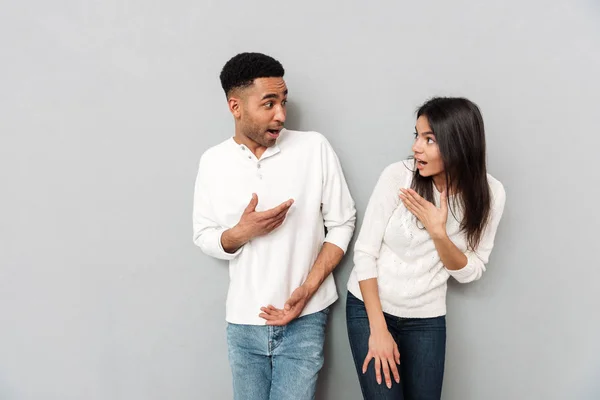 Jovem casal amoroso surpreso olhando um para o outro . — Fotografia de Stock