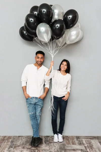 Sonriente pareja amorosa sosteniendo globos . — Foto de Stock