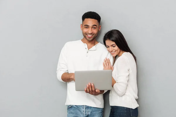 Feliz casal amoroso sobre parede cinza conversando por laptop — Fotografia de Stock