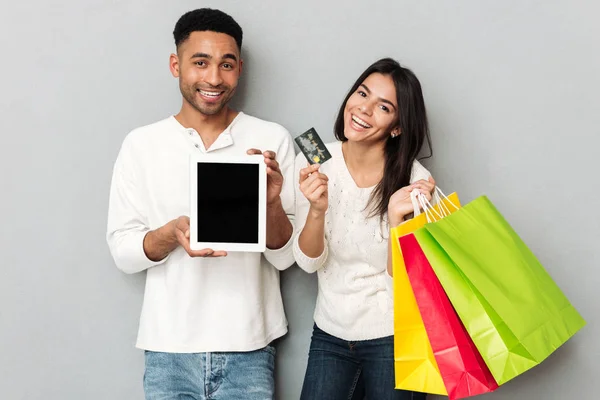 Чоловік і жінка, що показує кредитну картку і планшет з порожнім екраном — стокове фото