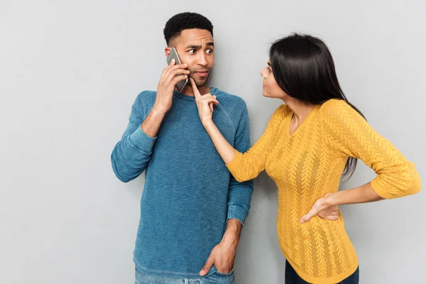 Женщина указывает на телефон своего мужа с требованием — стоковое фото