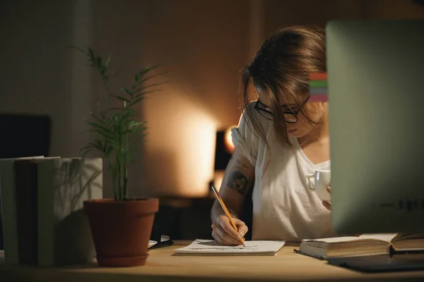 Концентрована молода жінка дизайнер пише нотатки за допомогою комп'ютера — стокове фото