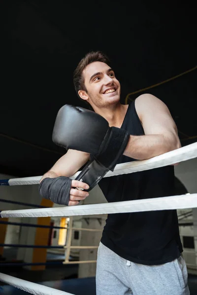 Boxer sorrindo usando luvas de boxe e olhando para longe — Fotografia de Stock