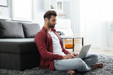 Kapalı dizüstü bilgisayar kullanırken evde oturan adam