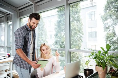 Tablet kullanırken coworking ofiste iki arkadaşları gülümseyerek