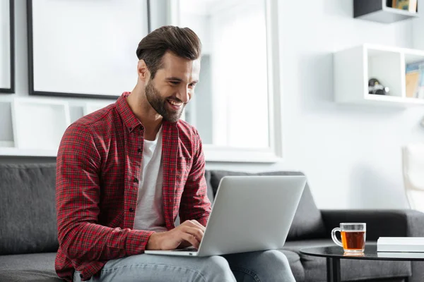 Fröhlicher junger Mann sitzt zu Hause drinnen — Stockfoto