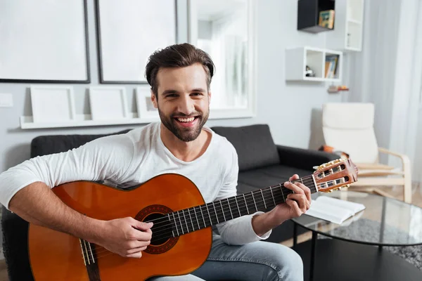 Hombre feliz tocando la guitarra. Mirando la cámara . — Foto de Stock