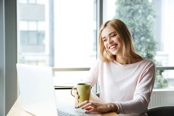 Glad dam som sitter i office coworking medan du använder bärbar dator — Stockfoto
