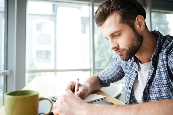 英俊的男人在办公室写笔记的时候 coworking — 图库照片