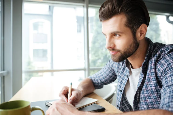 En kjekk mann som samarbeider mens han skriver notater – stockfoto