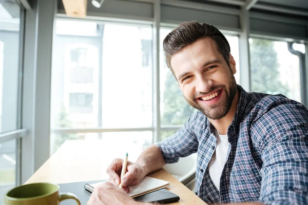 Veselý muž v úřadu coworking při psaní poznámek. — Stock fotografie