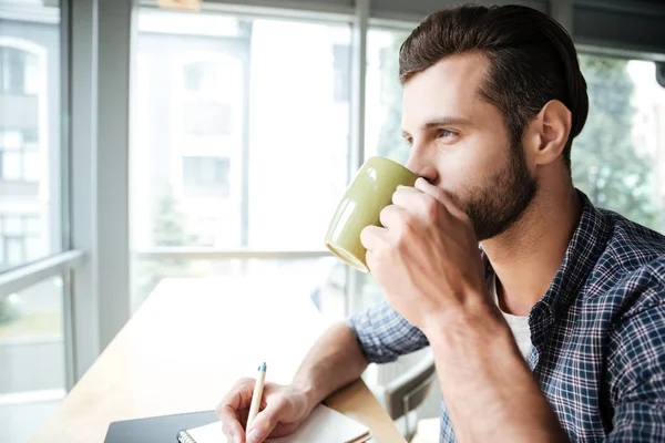 Hombre guapo en la oficina coworking mientras escribe notas beber té — Foto de Stock