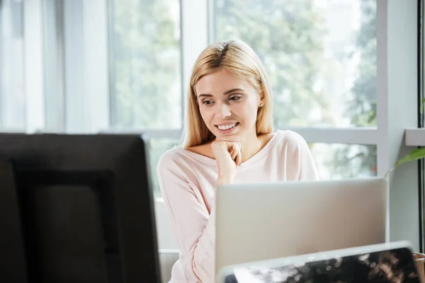 Glad dam som sitter i office coworking använder dator. — Stockfoto