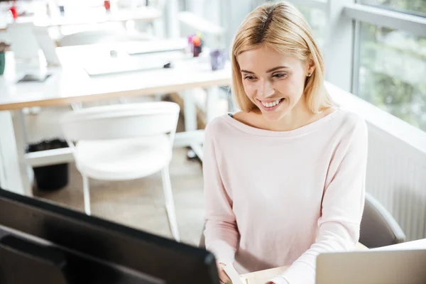 ผู้หญิงที่มีความสุขนั่งอยู่ในออฟฟิศ เพื่อนร่วมงานใช้คอมพิวเตอร์ . — ภาพถ่ายสต็อก