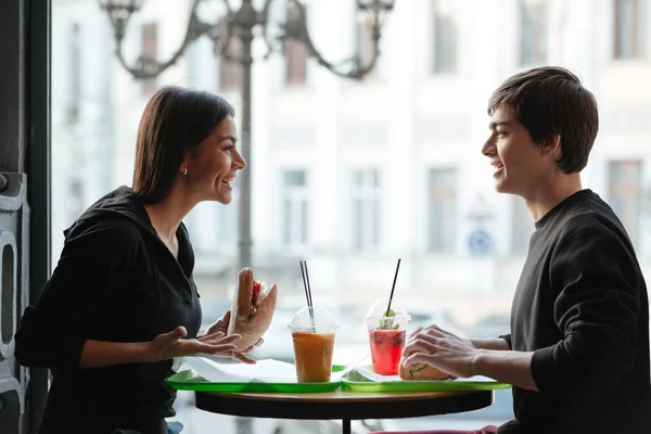 Lächelnder junger Mann sitzt mit Schwester im Café und trinkt Saft — Stockfoto